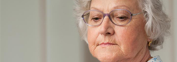 Senior aged woman looking down with sadness, indoor closeup shot