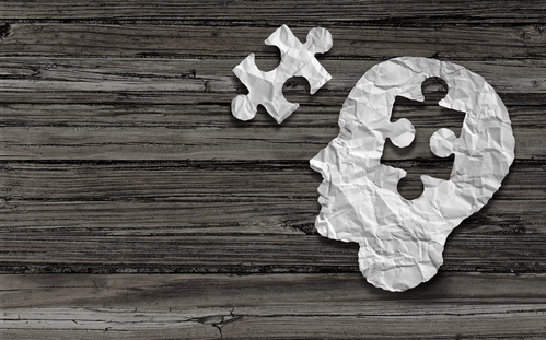Mental Health Symbol Puzzle And Head Brain Concept As A Human Face Profile Made From Crumpled White Paper With A Jigsaw Piece Cut Out On A Rustic Old Double Page Spread Horizontal Wood Background.