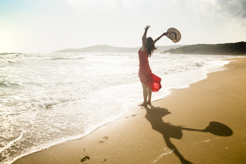 Happy Young Woman Raises Her Arms Towards The Sea